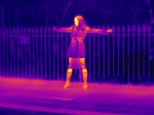 Woman standing against fence: thermal photography